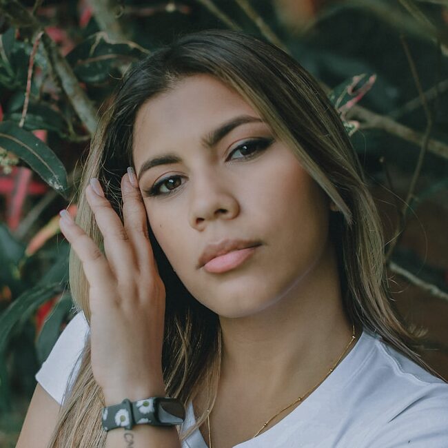 a beautiful young woman leaning against a tree